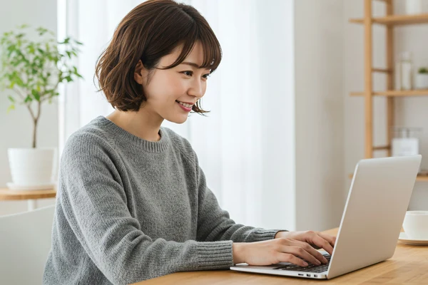整頓されたデスクでノートパソコンを使って微笑む女性
